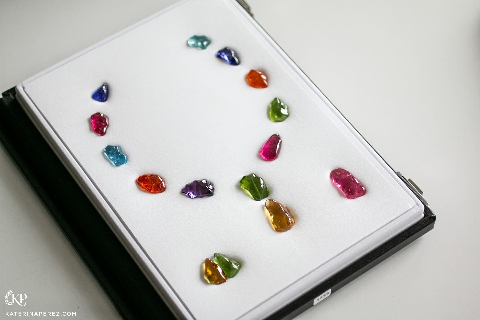 Baroque shaped coloured gemstones arranged in a necklace and asymmetric earring layout by Paul Wild, featuring tanzanite, aquamarine, yellow beryl, peridot, rubellite, amethyst and Mandarin garnet 