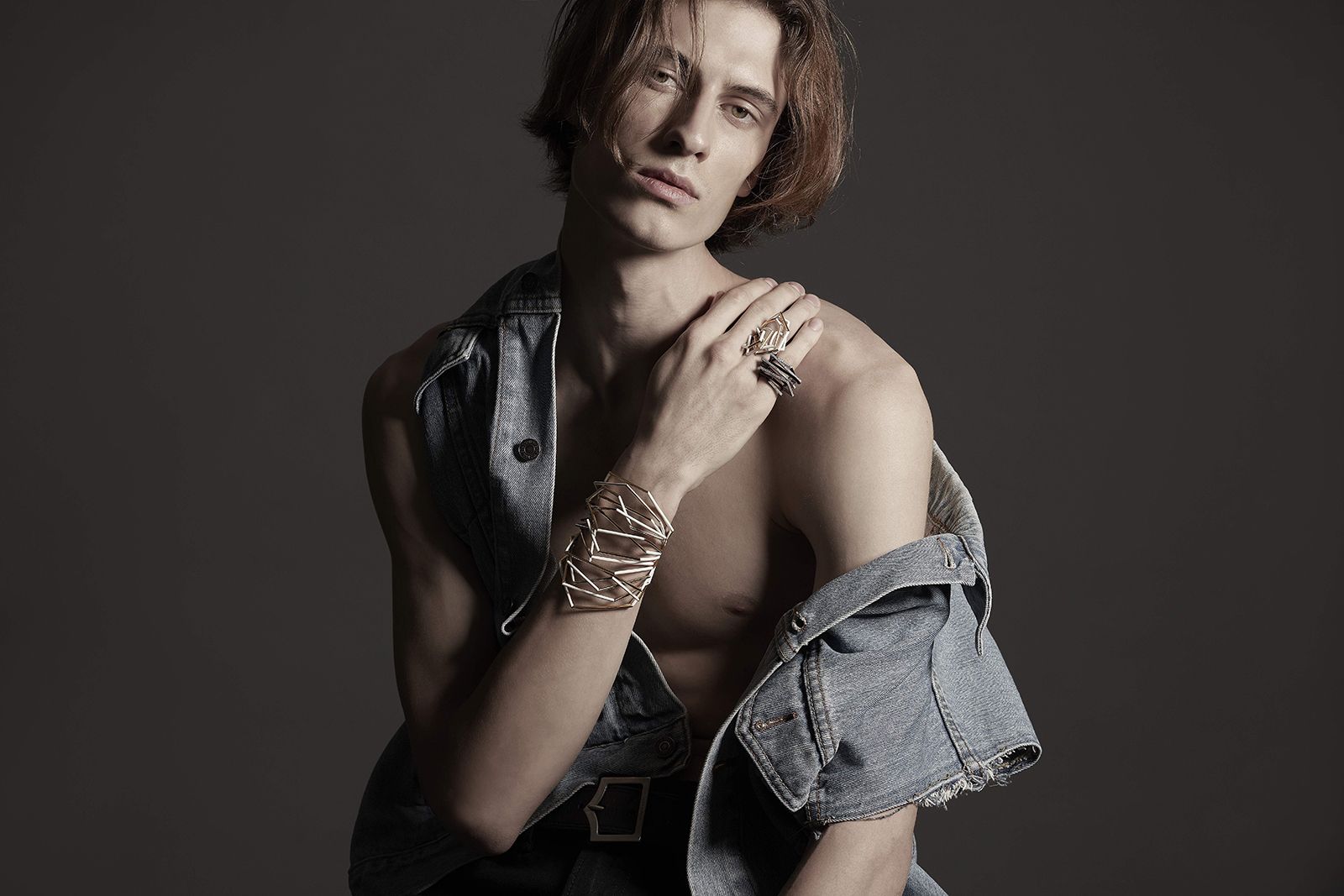 A male model wears Mike Joseph jewellery for SS22, including a cuff bracelet and rings