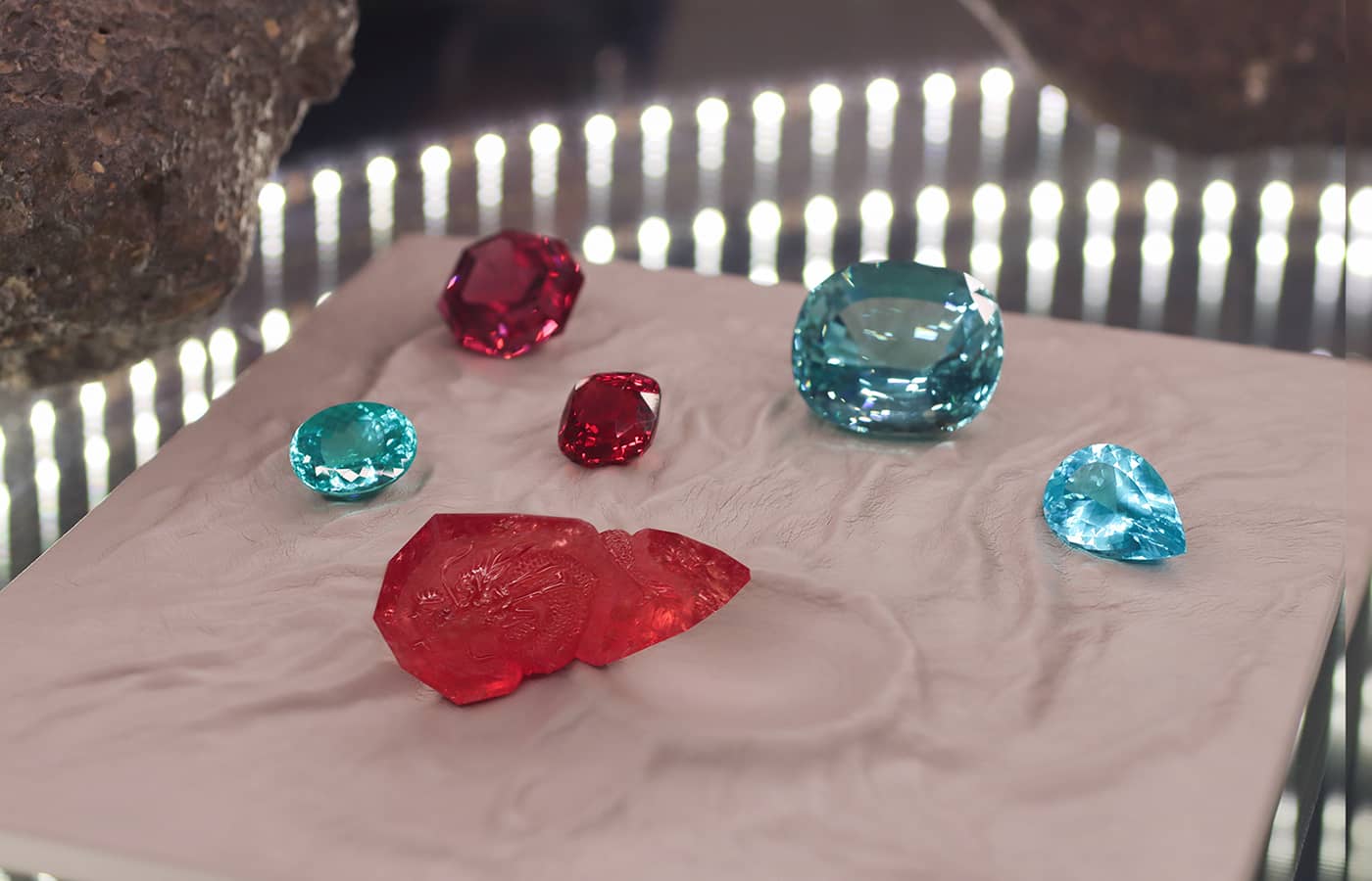Gemstones in Jochen Leën's private collection including red spinel, Paraiba tourmalines and a red beryl (front) with a dragon carving