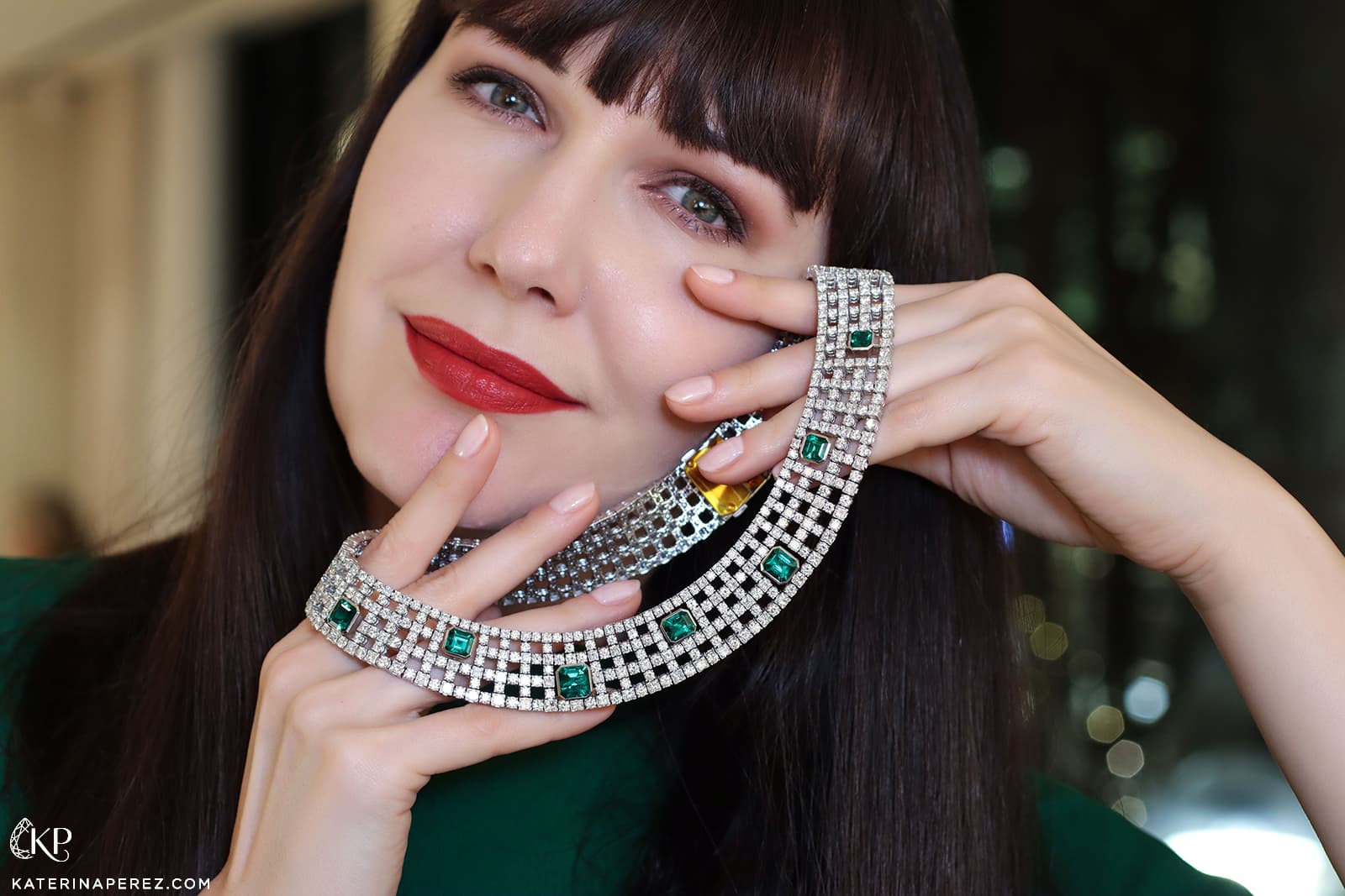 Katerina Perez holding an Art Deco inpsired emerald and diamond High Jewellery necklace by Bucherer Fine Jewellery