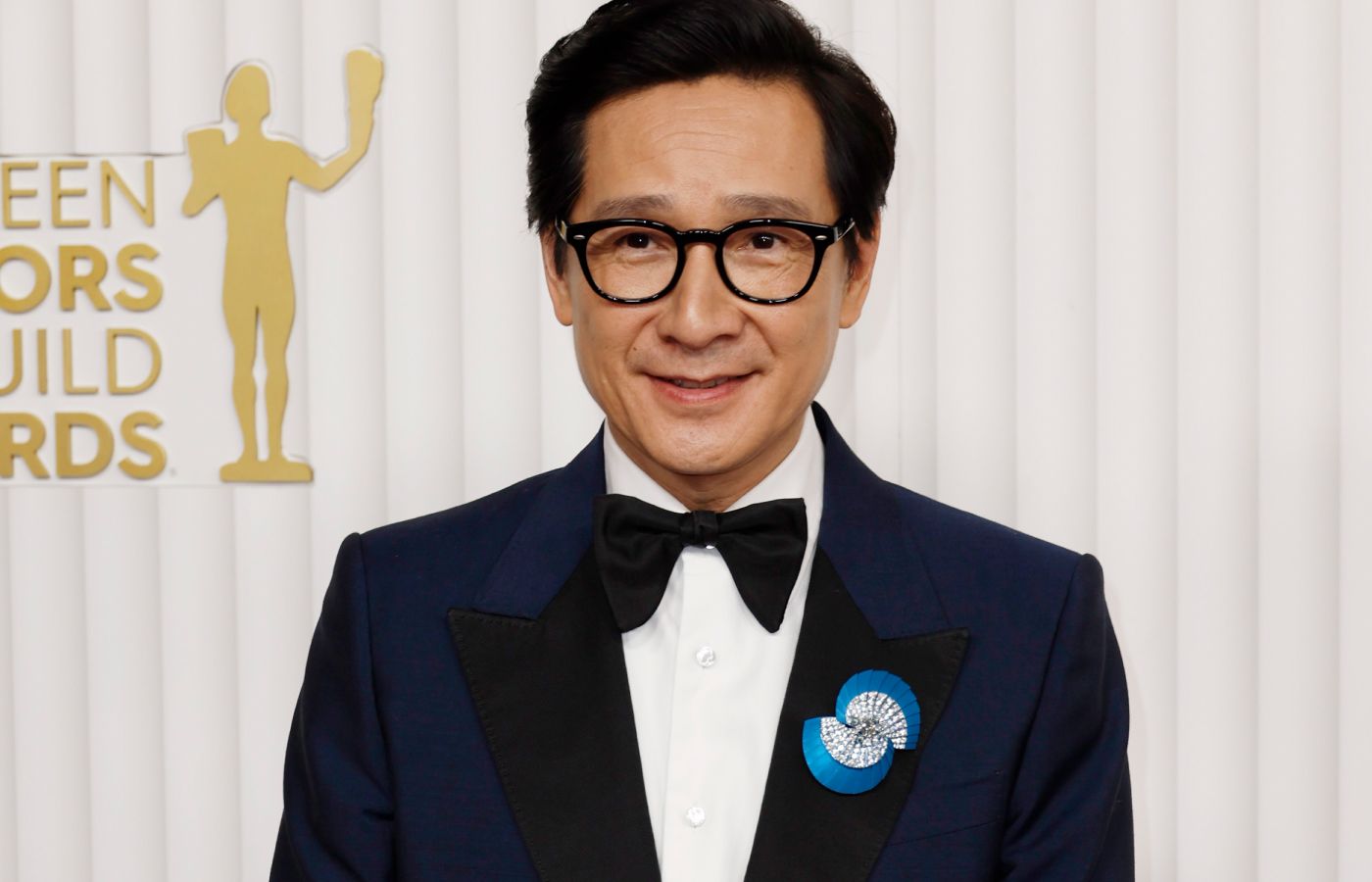 Actor Ke Huy Quan wears the De Beers The Alchemist of Light Ascending Shadows brooch with a 2.70-carat oval-shaped fancy grey diamond to the SAG Awards 2023