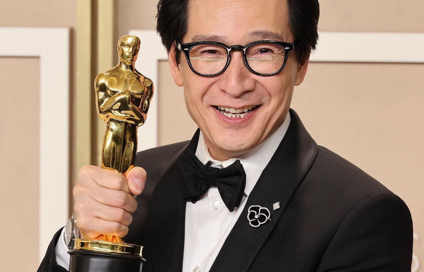 Ke Huy Quan wears Fred Leighton lapel pins at the 95th Academy Awards, including a diamond and black velvet pansy and a 2.50 carat lozenge-shaped diamond