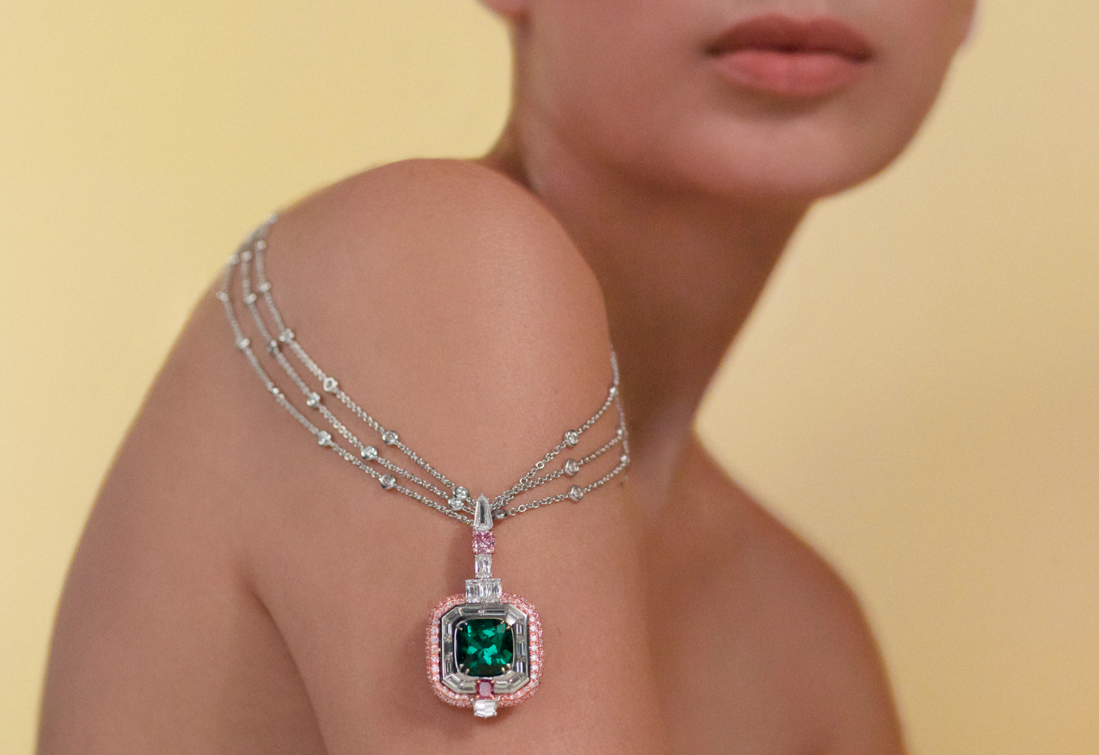 Model wearing the Muzo Emerald Colombia Earth Magic II necklace in gold, platinum, a 7.66-ct Muzo emerald, a 1.06 carat fancy intense purplish pink Argyle diamond,  0.43 carat, a fancy purplish red Argyle diamond and white diamonds from the Green Jewel Tradition collection