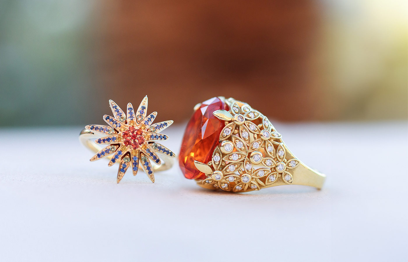 Lisa Nik rings including the multi-coloured sapphire Star ring from the Rainbow collection and a 9.61 carat Mexican fire opal cocktail ring from the Colors collection, both in 18k yellow gold 