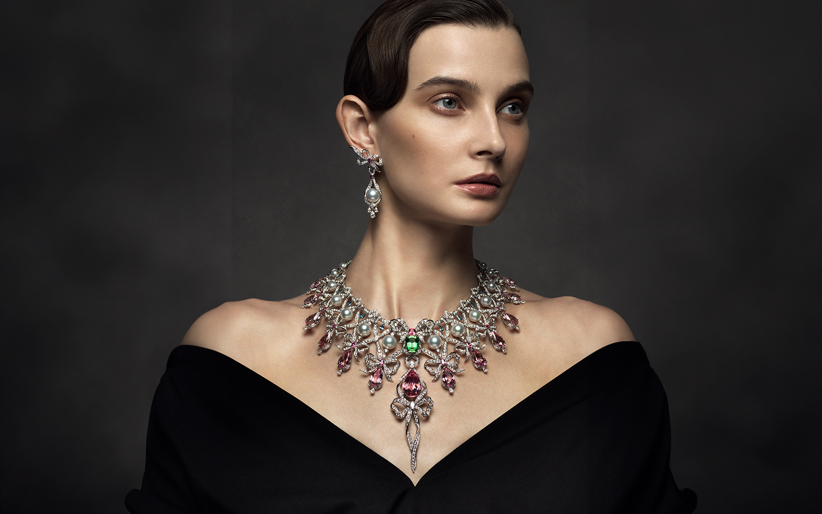 A model wears a Mikimoto Rococo-inspired necklace with Akoya cultured pearls, pear-shaped morganites, a green tourmaline, pink spinel, oval-shaped pink sapphires, diamonds and pear-shaped aquamarines, all set in 18k white gold, alongside the matching earrings from ‘The Bows’ High Jewellery collection