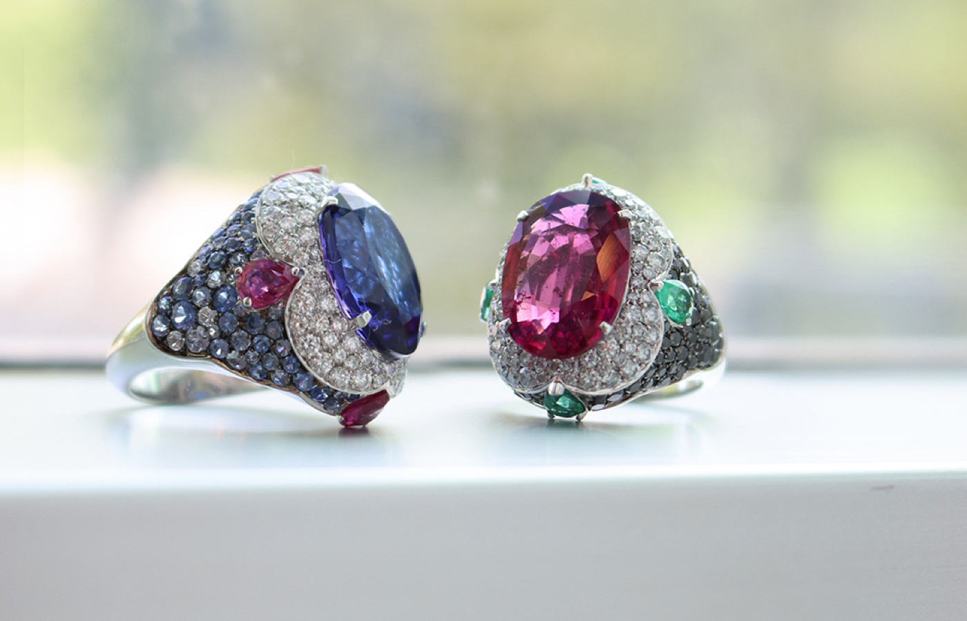 Maison J’OR Merletto collection cocktail rings, including a 9.21 carat tanzanite ring with 1.47 carats of rubies, 1.26 carats of diamonds and 2.01 carats of blue sapphires, and a 6.18 carat rubellite ring with 0.98 carats of pear-cut emeralds, 1.26 carats of diamonds, and 1.40 carats of black diamonds, both in 18k white gold 